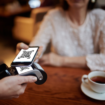 Smartphone con schermata QRcode che effettua il pagamento su POS