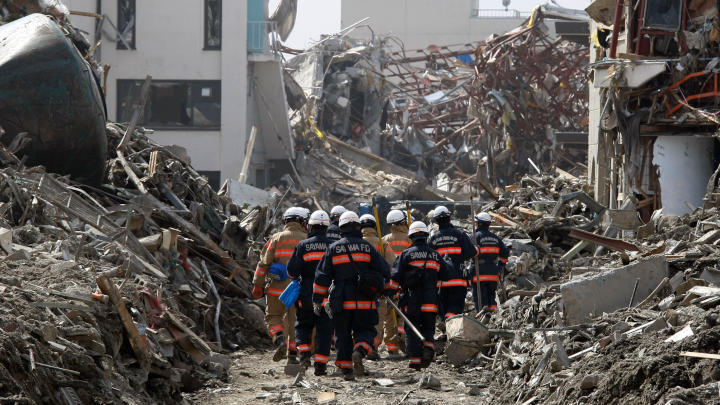 Una squadra di soccorso si muove tra le macerie degli edifici